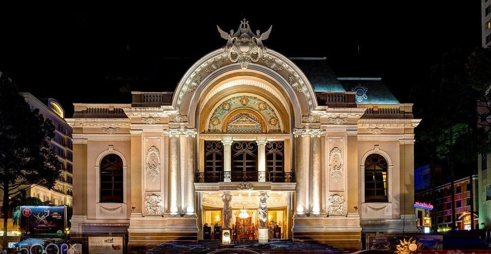 The Ho Chi Minh City Opera House glows beautifully at night, showcasing its French colonial architecture with intricate carvings and a grand arched entrance in the heart of Saigon